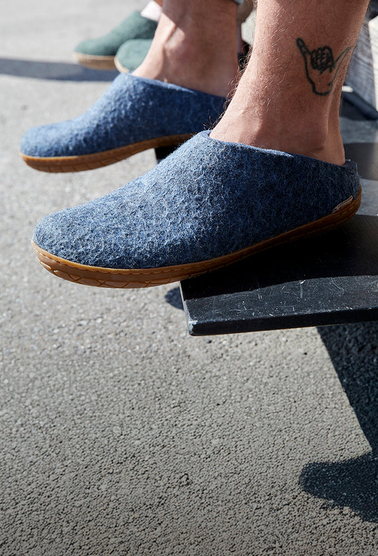 A close up picture of a person wearing glerups slip-ons in the color Denim with natural rubber sole. 
